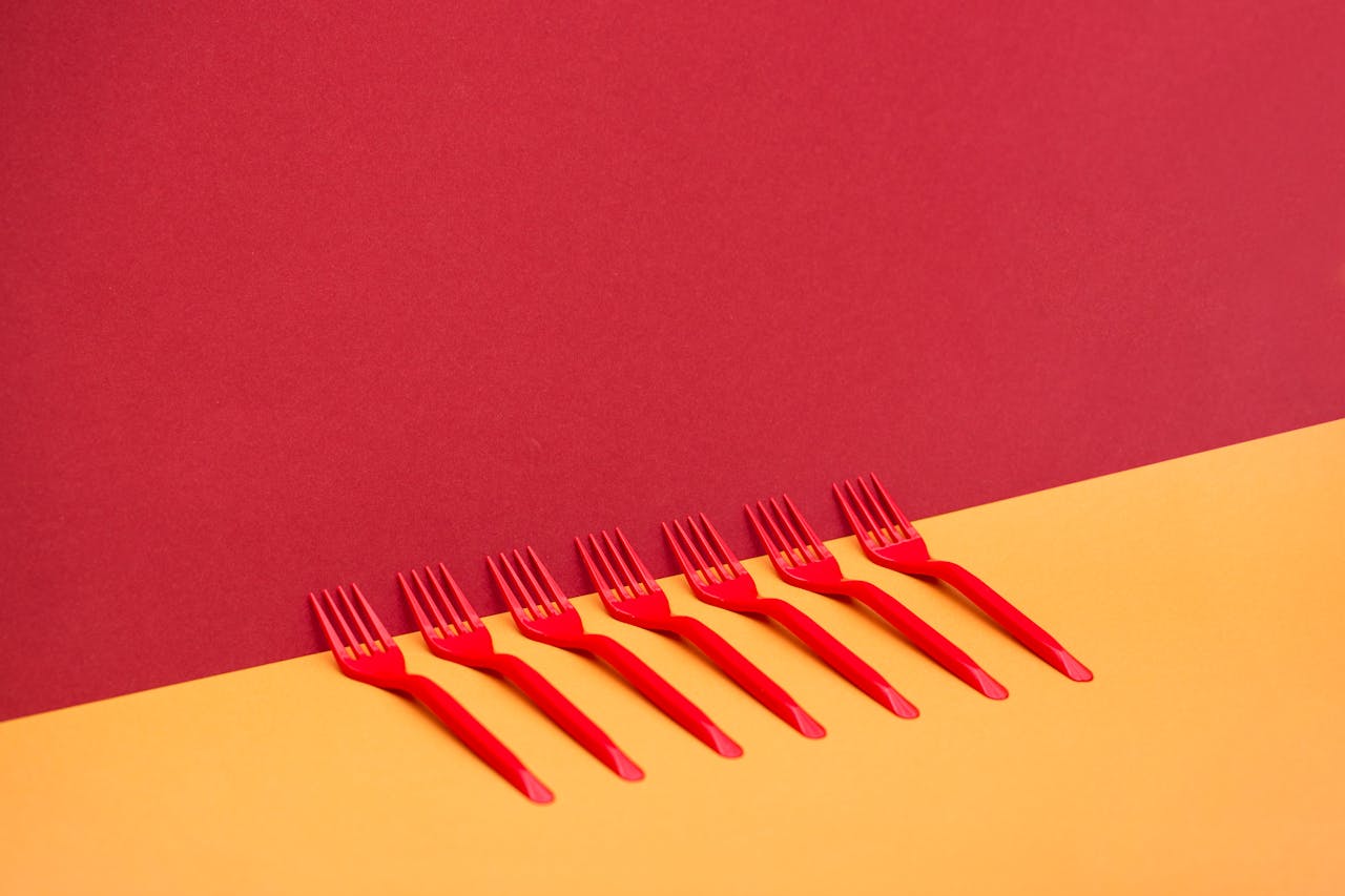 Bright red plastic forks arranged on a vivid two-toned background for a modern look.